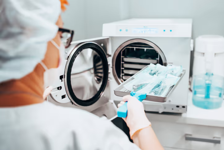 Medical professional loading sterilized instruments into an autoclave machine.