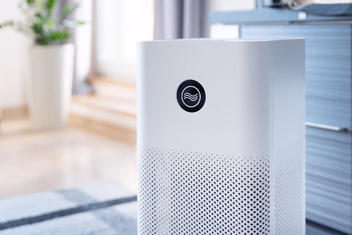 White rectangular air purifier with circular display showing airflow icon in a modern indoor setting.