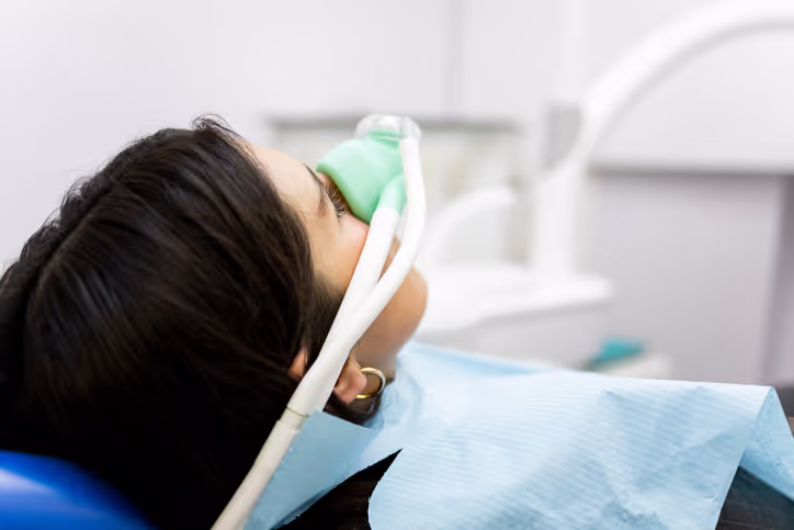 Patient reclining in a dental chair wearing a nasal mask for nitrous oxide sedation.