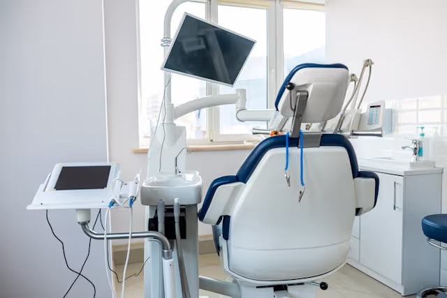 Modern dental chair with attached monitor and dental equipment in a bright clinic room.