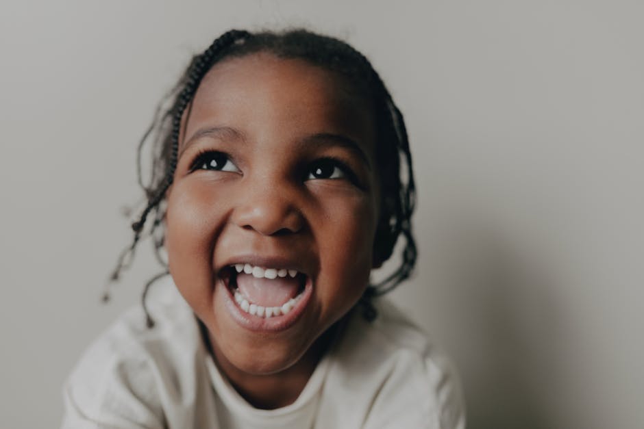 Happy young girl with braided hair smiling joyfully in a close-up shot.